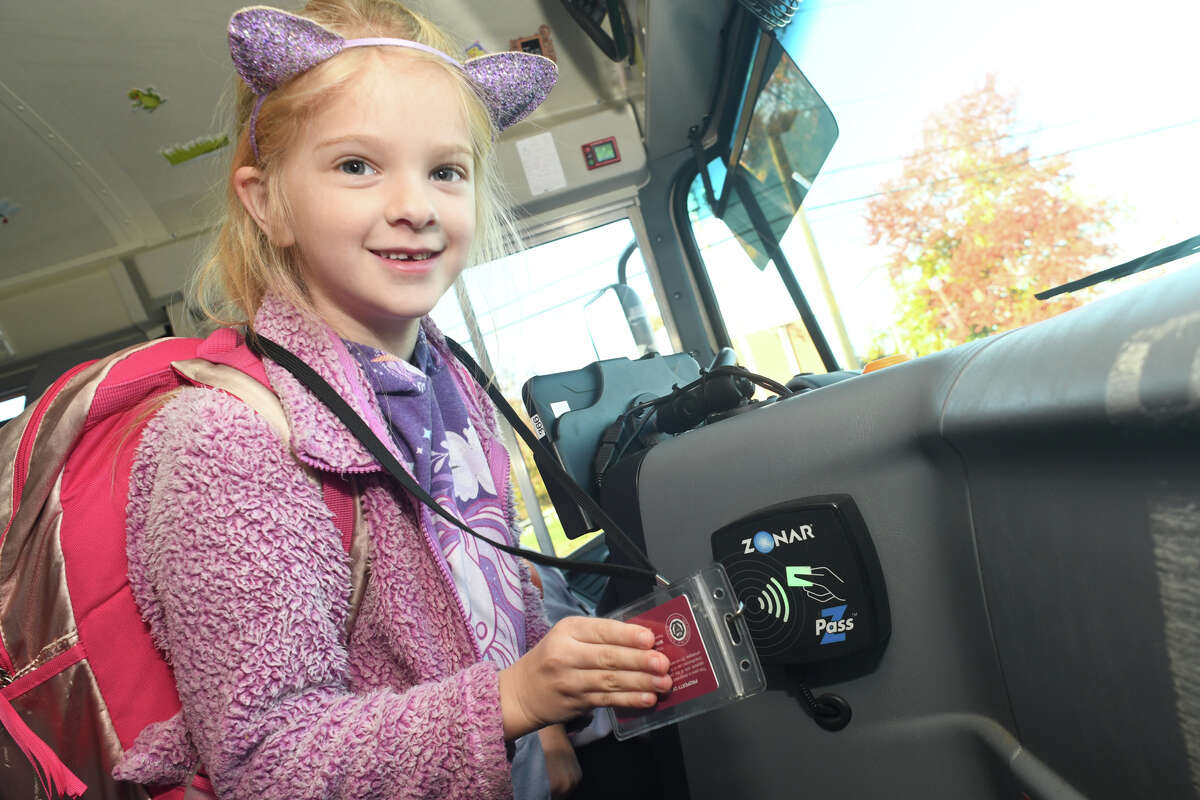 First grader Clarice Farrington scans her Zonar Z Pass as her school bus arrives at Meadowside Elementary School, in Milford, Conn. Nov. 3, 2022.