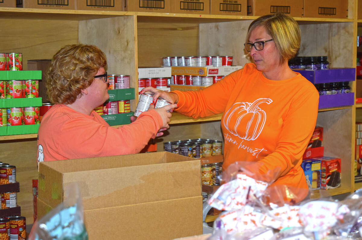 Kelsey (left) and Melissa Hall pack a box with canned and non-perishable food items at the Jacksonville Food Bank.