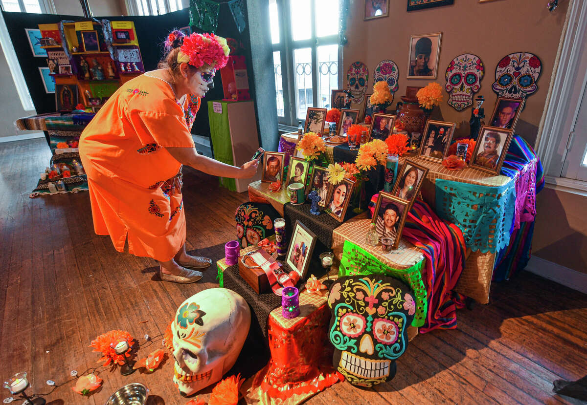 Edith Vasquez uses her phone to take photos of her altar dedicated to the Gonzalez-Macias-Vasquez family at the Laredo Center for the Arts during the Annual Dia de los Muertos Cultural Celebration.