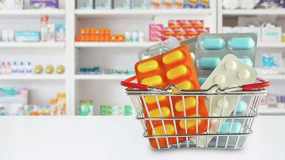 Medicine pills package in shopping basket with pharmacy drugstore shelves blur background