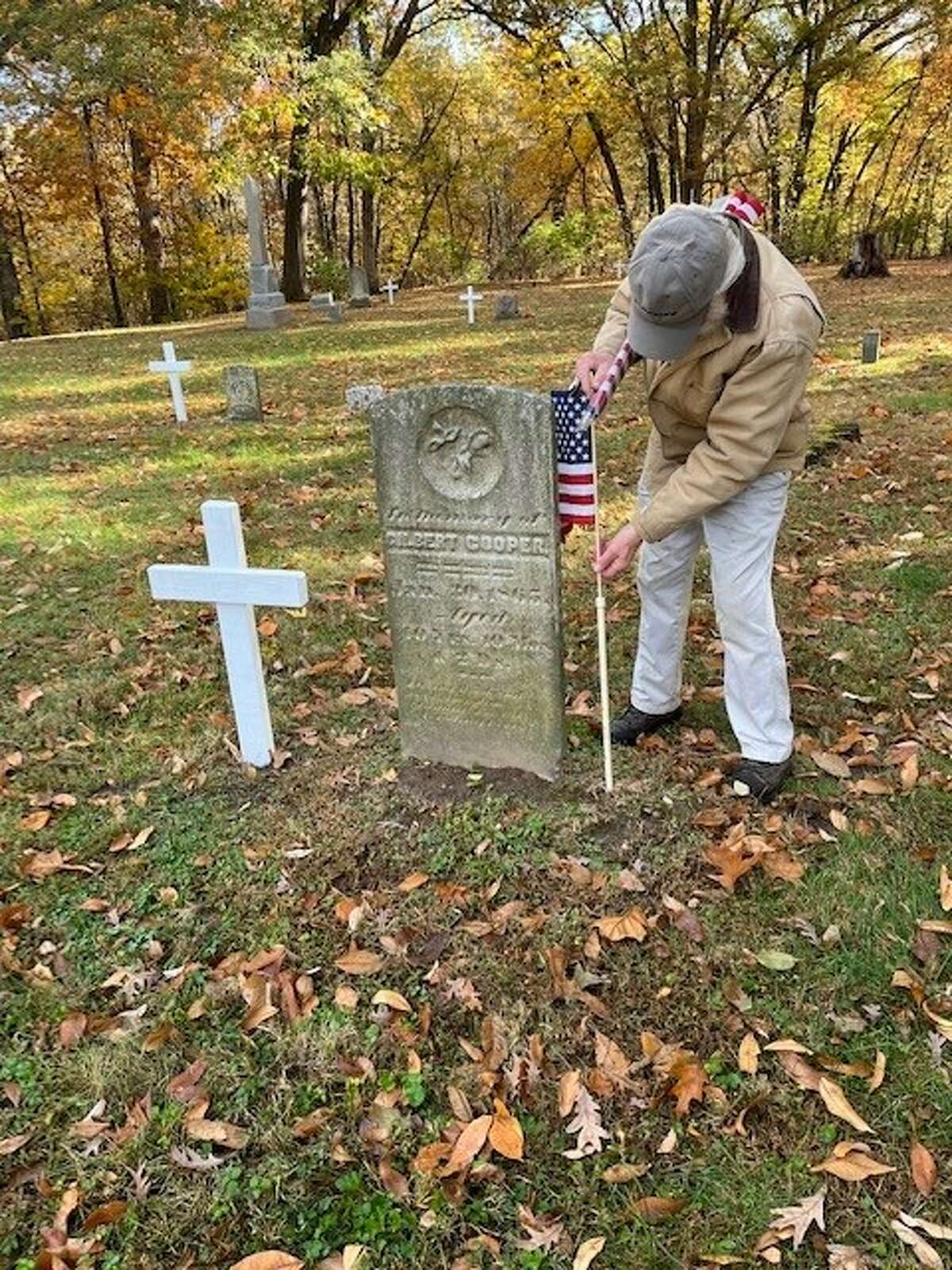 Wood River Cemetery Commission Chairman Rob LaMarsh replaces a flag at a headstone at Vaughn Hill Cemetery. 