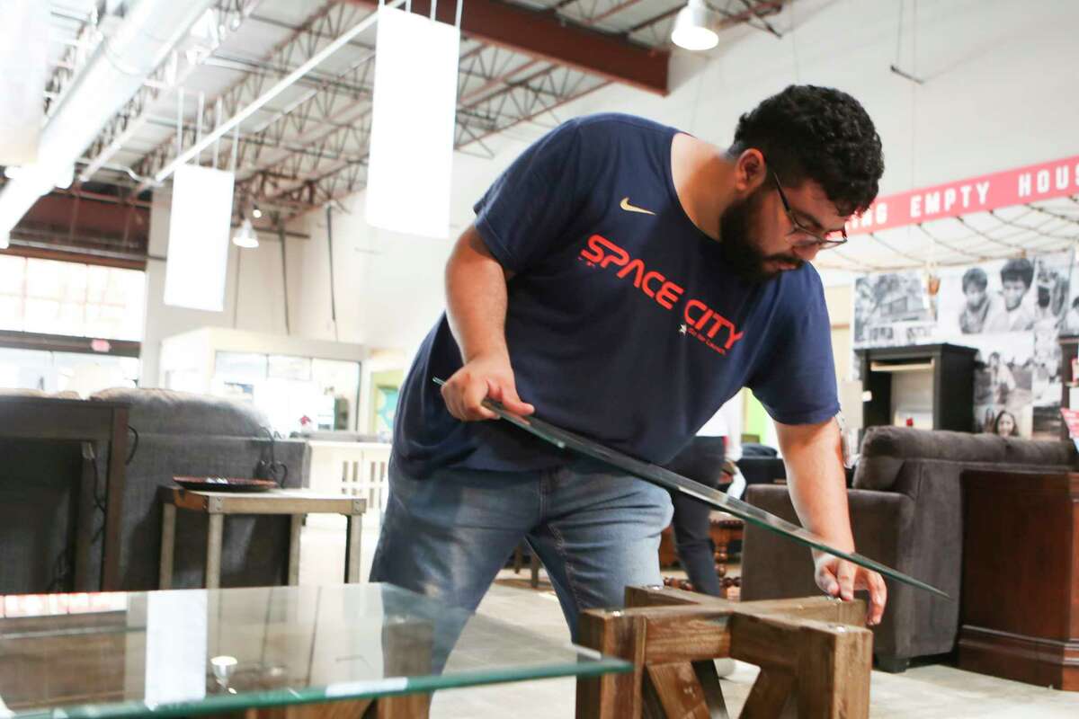 Arturo Estrada helps arrange furniture as The Furniture Bank Houston celebrates its 30th anniversary on Friday, Nov. 4, 2022, in The Woodlands. The organization partners with several non-profits to operates as a furniture outlet, warehouse and helps recycle mattresses.