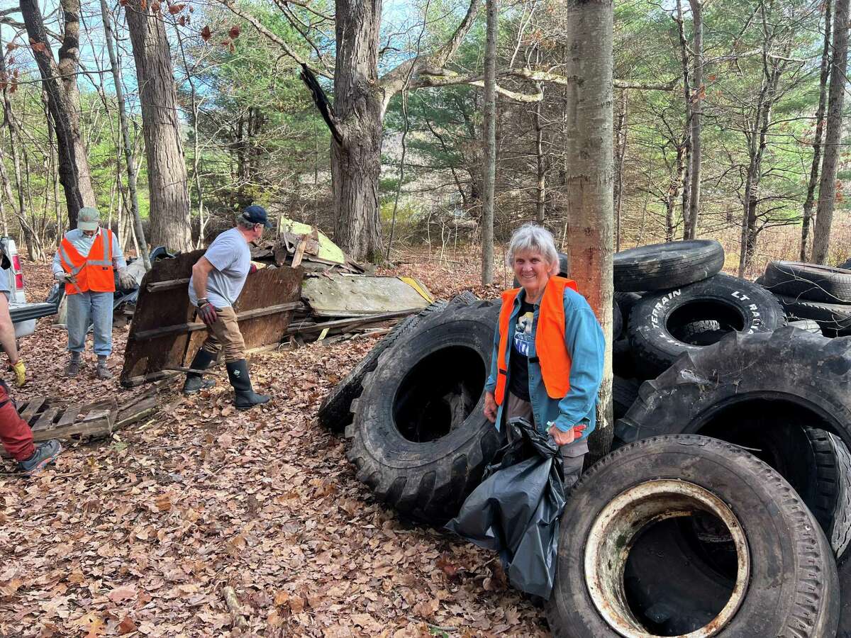 Donna Simms stands in front of the tires pulled from the Dill Brook Community Forest in Memory of Robert Simms that she helped preserve with a donation in the town of Petersburgh on Saturday, Nov. 5, 2022.