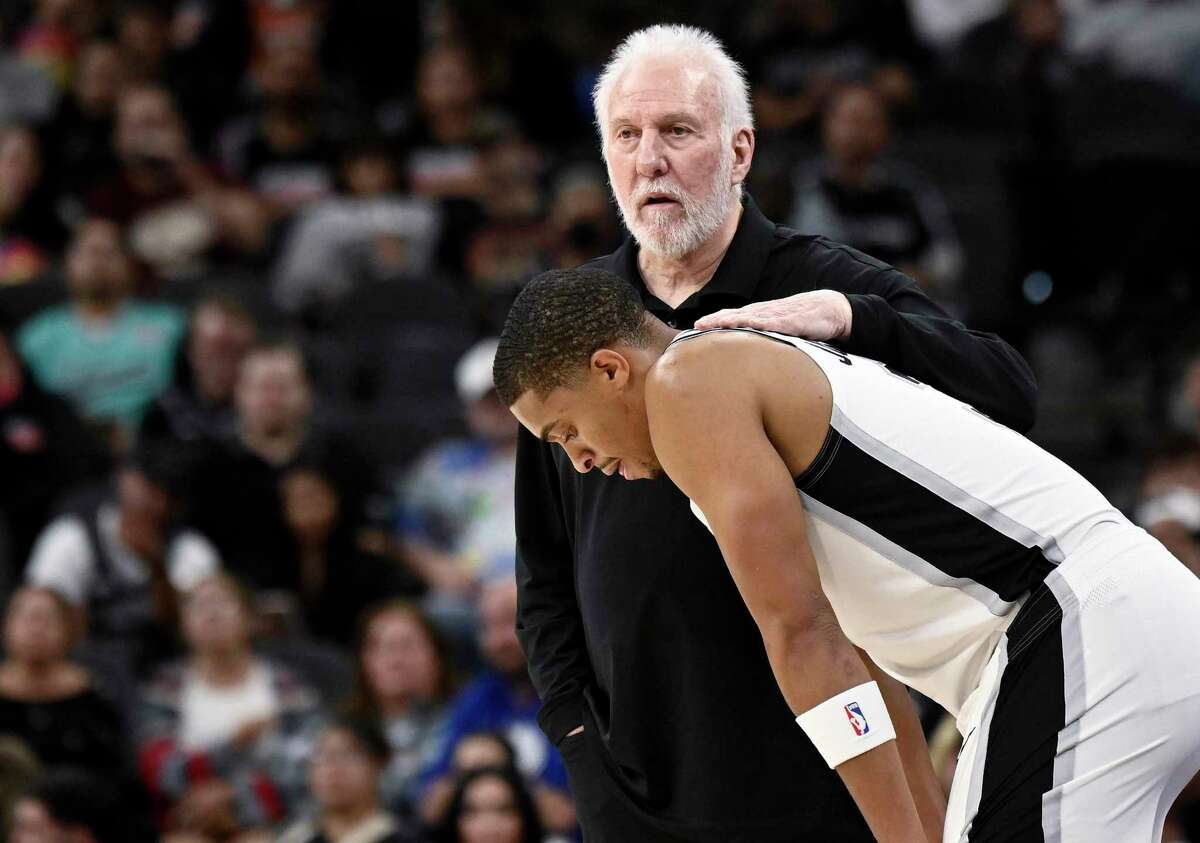 San Antonio Spurs head coach Gregg Popovich, top, speaks with Spurs forward Keldon Johnson during a timeout in the first half of an NBA basketball game against the Minnesota Timberwolves, Sunday, Oct. 30, 2022, in San Antonio. (AP Photo/Darren Abate)