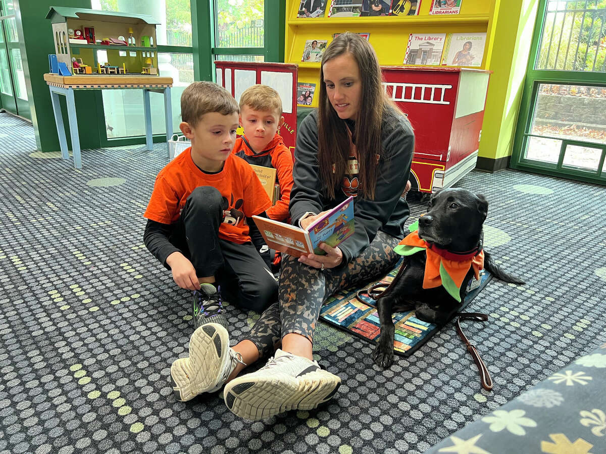 Tanya Holler, of Edwardsville, helps her son Kendrick Holler, left, 6, read to therapy dog Woody, 8, while his little brother, Axel Holler, 4, looks at the pictures in the book at the Edwardsville Public Library Saturday.