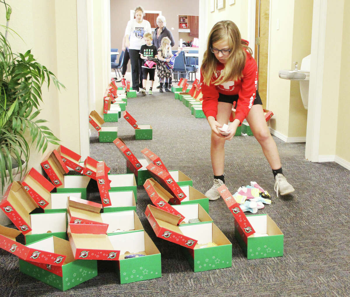 Eva Martin, 10, drops items into shoeboxes during a Samaritan's Purse Operation Christmas Child project at the Ivy Heights Church of God in Wood River Saturday. Shoeboxes are filled with toys, small articles of clothing, school supplies and other items, then shipped to needy children throughout the world.