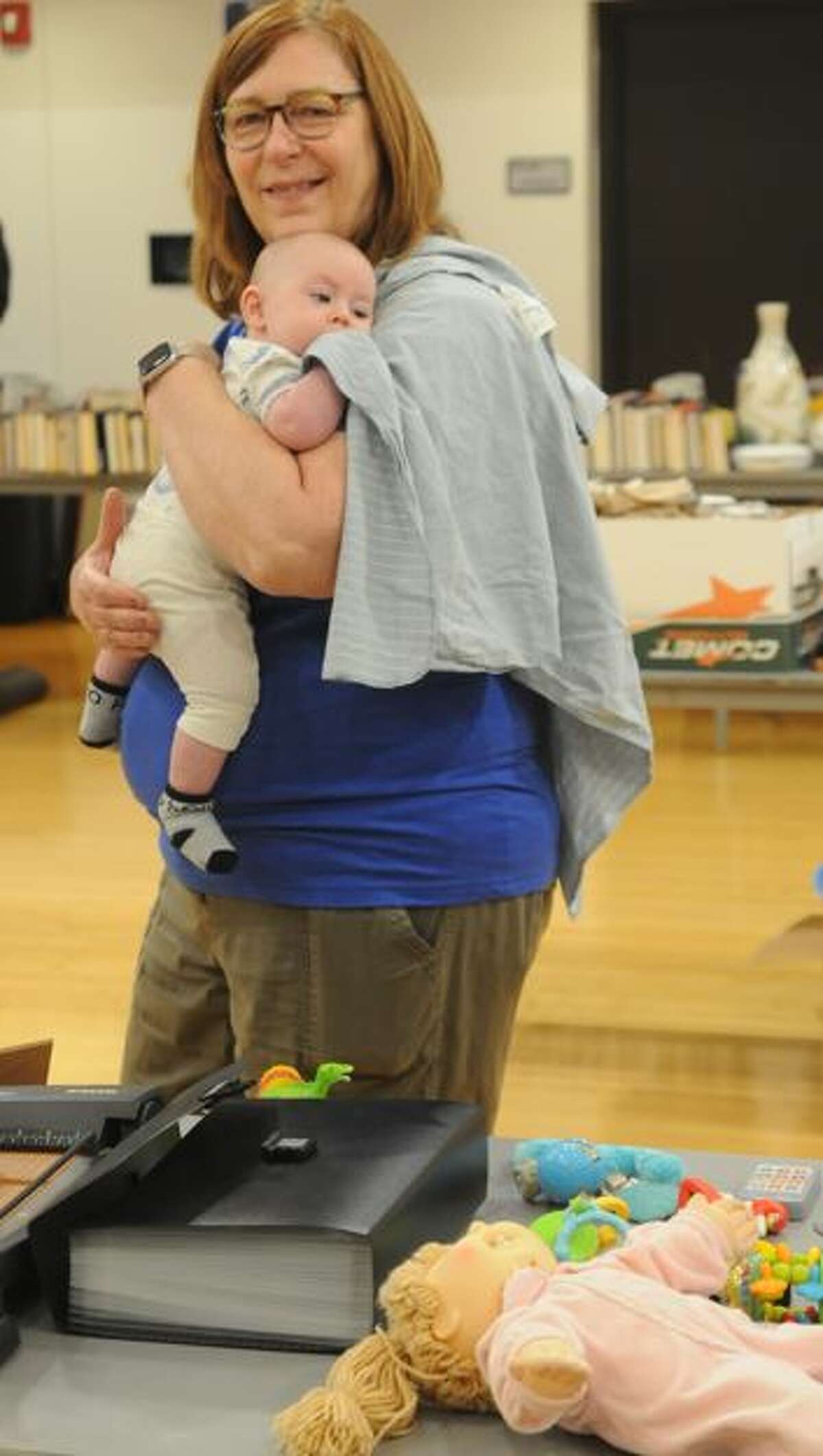 Barb Van Walleghen of Jerseyville holds a friend's baby as she shops during the Jensen's Little Heart Rummage Sale on Saturday.   