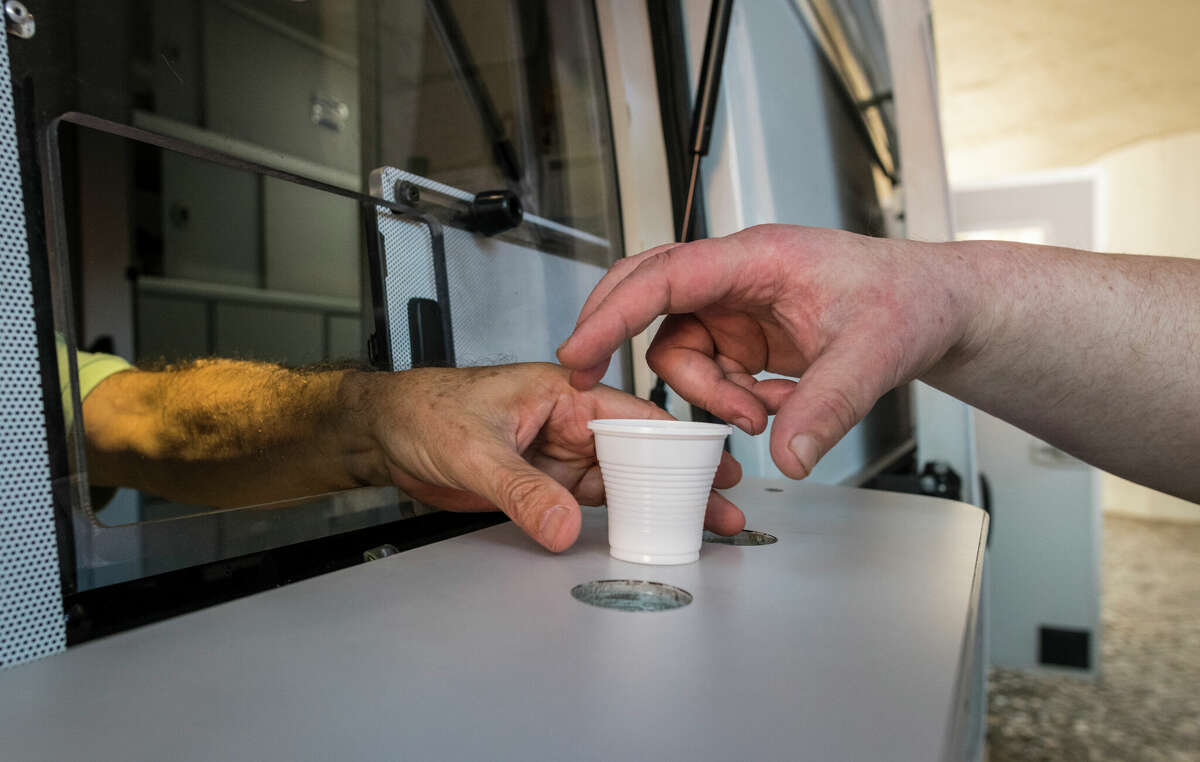 LISBON, PORTUGAL - OCTOBER 04: A patient is handed his daily dose of 85 milligrams of methadone by male nurse Joao Matos from a van parked near Praca Espanha on October 04, 2017 in Lisbon, Portugal. The daily methadone program, run by the Ares do Pinhal Association for Social Inclusion, is part of Portugal's radical turn from 2001 decriminalizing drug use and placing emphasis on treating drug addiction with a public health approach. Nowadays the number of heroin addicts in Portugal has gone down by half from 100,000 people before the policy began and the country has one of Europe's lowest drug mortality rates. The number of people with HIV also dropped, from 1,001 new cases in 2001 to 56 cases in 2012. (Photo by Horacio Villalobos - Corbis/Corbis via Getty Images)