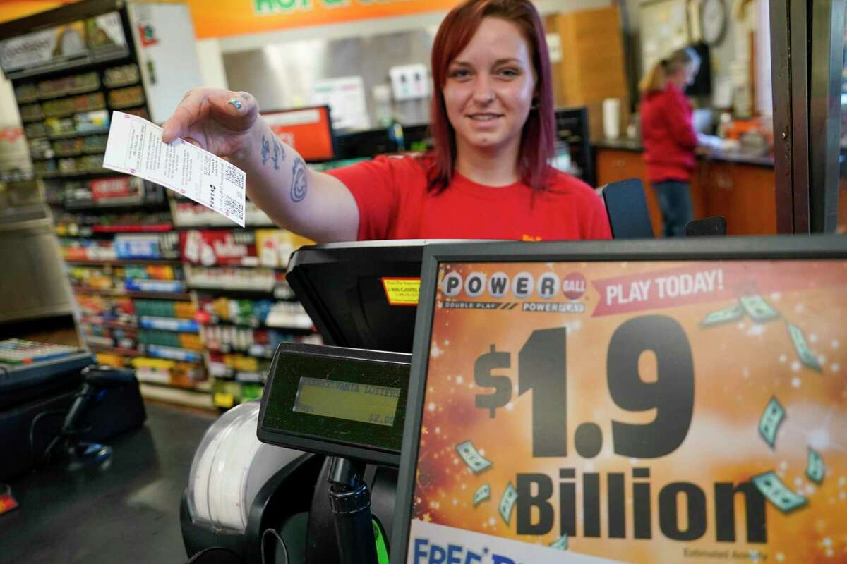 Crystal Baptiste hands a ticket to a customer for the record $1.9 billion Monday Powerball drawing at a convenience store in Renfrew, Pa. Someone in Southern California bought the winning jackpot ticket and one of the $1.1 million winners bought a ticket in San Francisco.