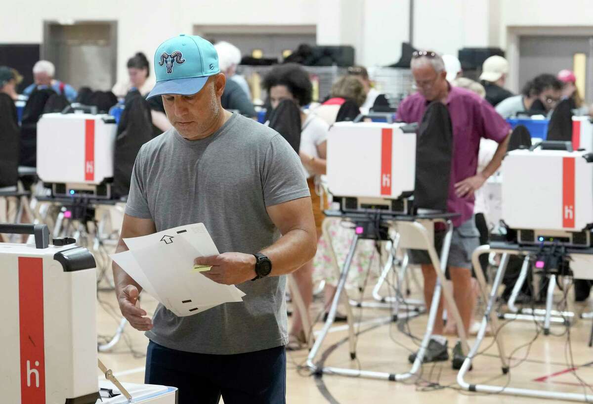 2022 年 11 月 8 日火曜日、ヒューストンの選挙日、1475 W グレイ ストリートのウエスト グレイ マルチサービス センターで投票用紙をスキャンする男性。