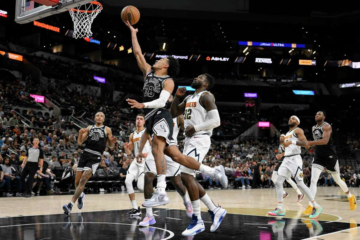 San Antonio Spurs' Tre Jones (33) goes to the basket past Denver Nuggets' Jeff Green (32) during the second half of an NBA basketball game Monday, Nov. 7, 2022, in San Antonio. The Nuggets won 115-109. (AP Photo/Darren Abate)
