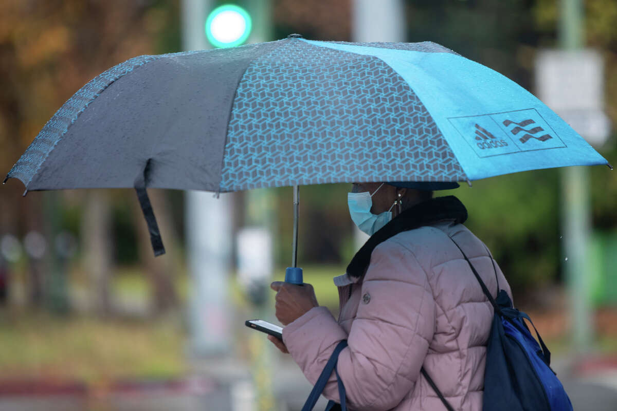 A woman uses an umbrella during a rainfall in Oakland, Calif. on Nov. 8, 2022.