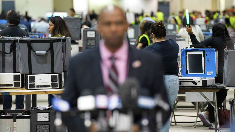 Workers verify ballots as Clifford Tatum, Harris County Elections Administrator, addresses the media at NRG Arena on Tuesday, Nov. 8, 2022 in Houston.