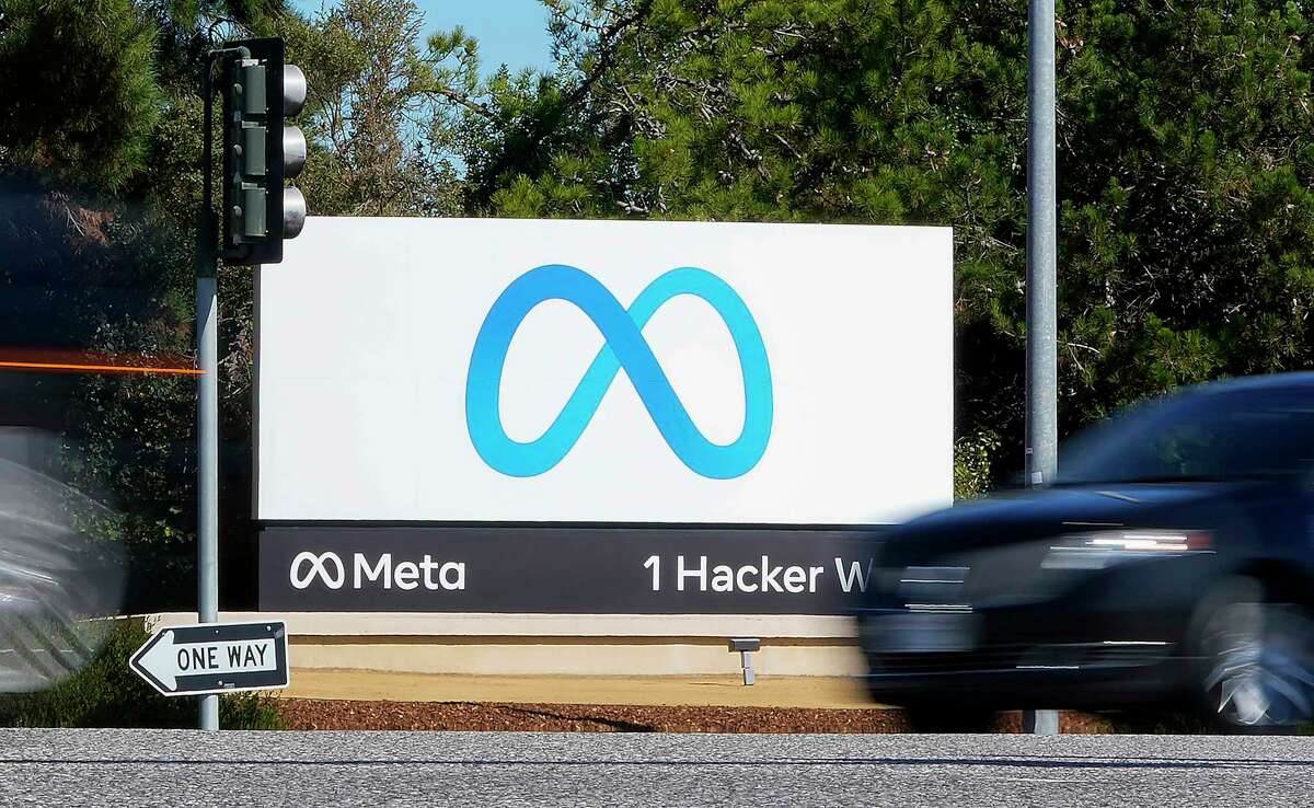 FILE - A car passes Facebook's new Meta logo on a sign at the company headquarters on Oct. 28, 2021, in Menlo Park, Calif. Facebook parent Meta is laying off 13% of its employees as it contends with faltering revenue and broader tech industry woes.