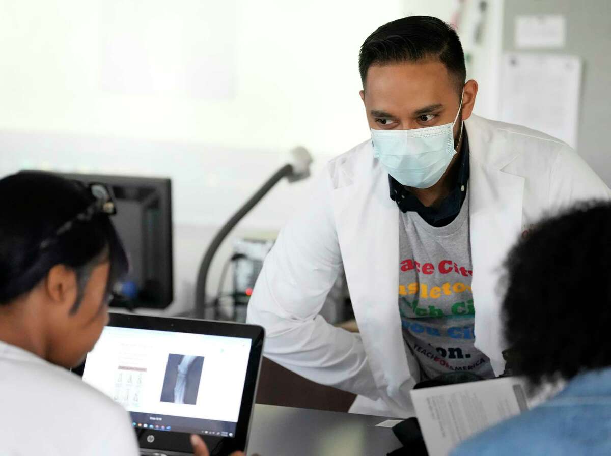 Nabeel Ahmad, a third-year aesculapian  pupil  astatine  the University of Houston College of Medicine, works   with students Jack Yates High School Wednesday, Nov. 9, 2022, successful  Houston. In the Healthcare Collaborative, aesculapian  students service  arsenic  mentors to students who are funny   successful  pursuing a vocation  successful  wellness  sciences.