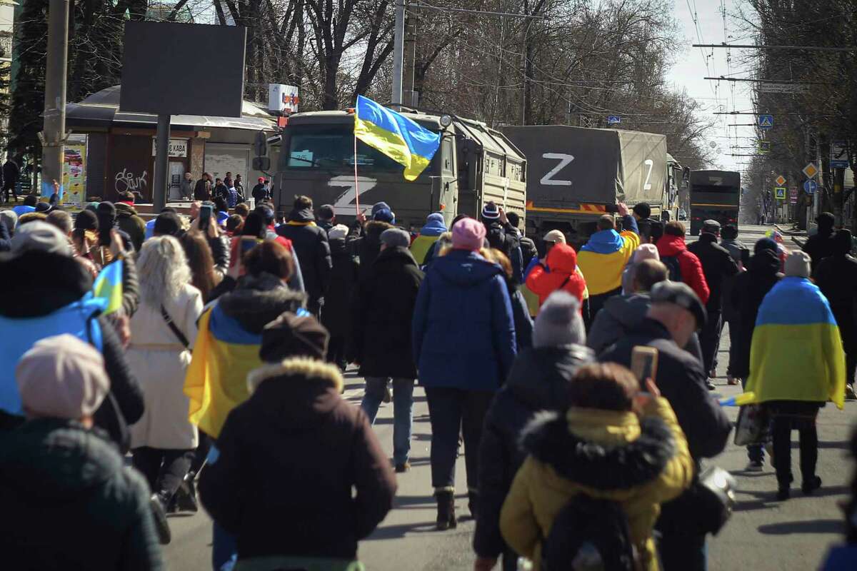 FILE - People with Ukrainian flags walk towards Russian army trucks during a rally against the Russian occupation in Kherson, Ukraine, Sunday, March 20, 2022. Ukrainian officials have acknowledged that Russian troops had no choice but to flee a key southern city, but stopped short of declaring victory in Kherson.