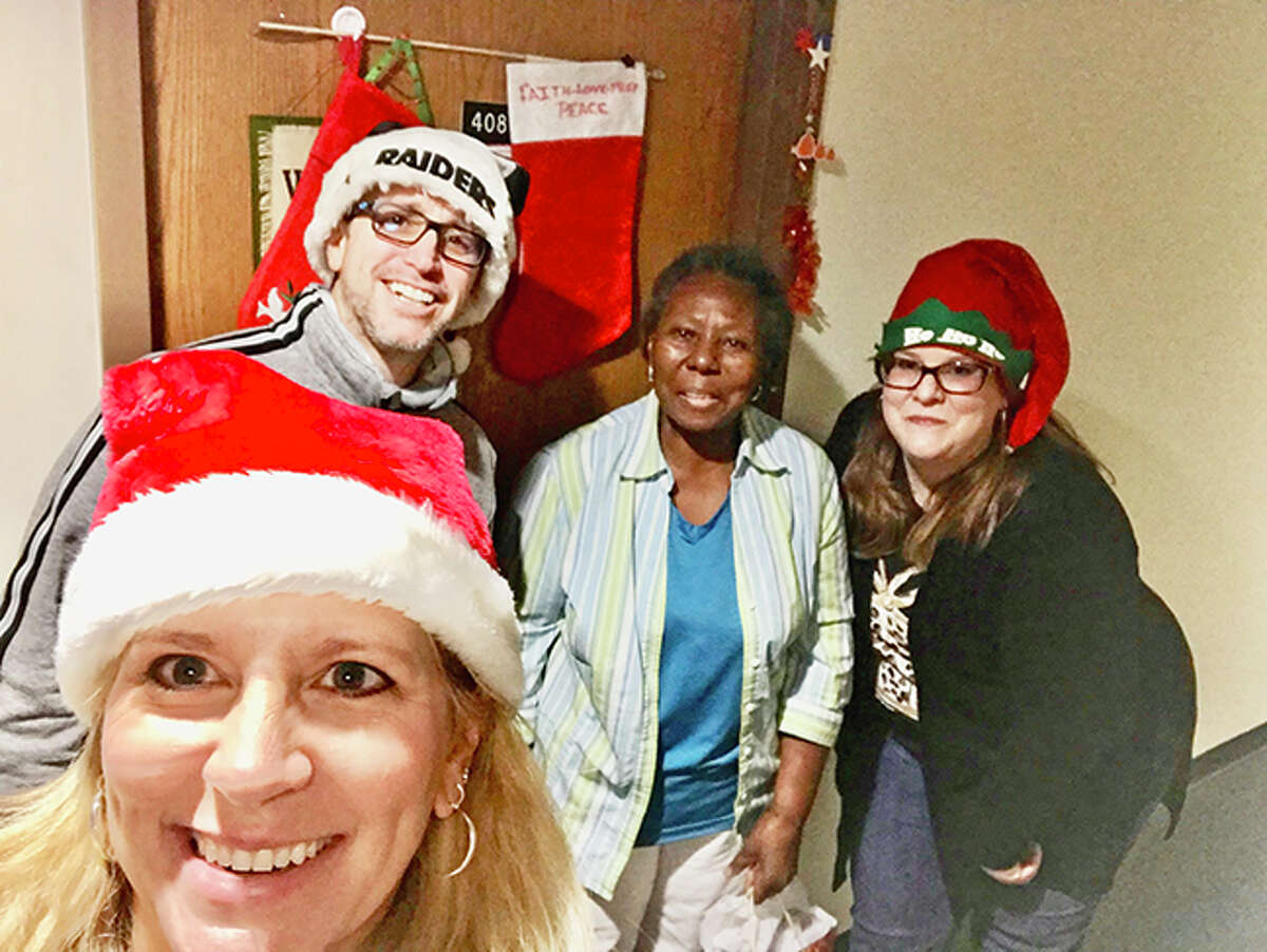 Mamie West, second from right, receives her holiday from Home Instead employees during last year's "Be a Santa to a Senior" program.