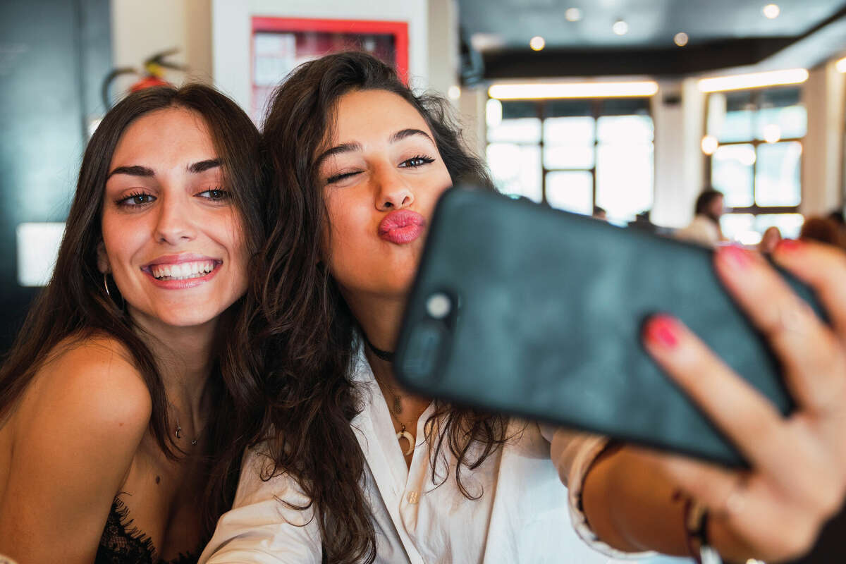Two happy women take a selfie in a coffee shop. 