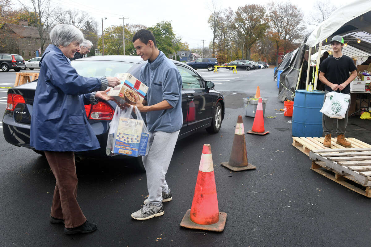 Scout Emilio Contreras helps a woman as she drops off food at Boy Scout Troop 1’s food drive at Wasson Field, in Milford, Conn. Nov. 11, 2022.