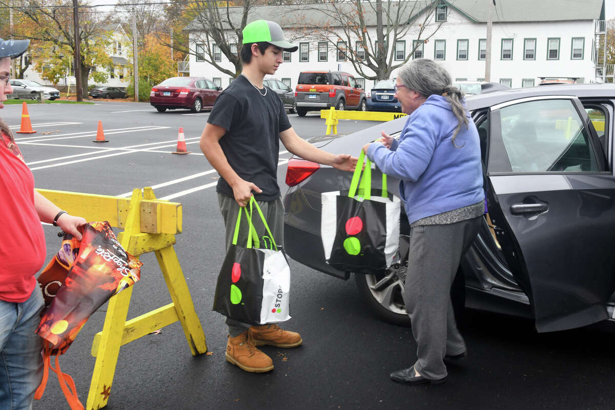 Scout Matt Wright helps a woman as she drops off food at Boy Scout Troop 1’s food drive at Wasson Field, in Milford, Conn. Nov. 11, 2022.