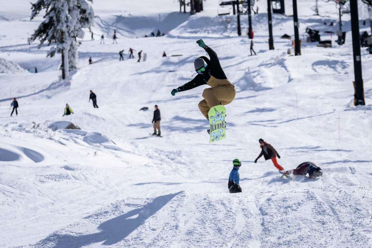 2022年11月11日，在加州特拉基的北方度假胜地，滑雪季节开幕日，一名单板滑雪运动员跳过一座小山丘。