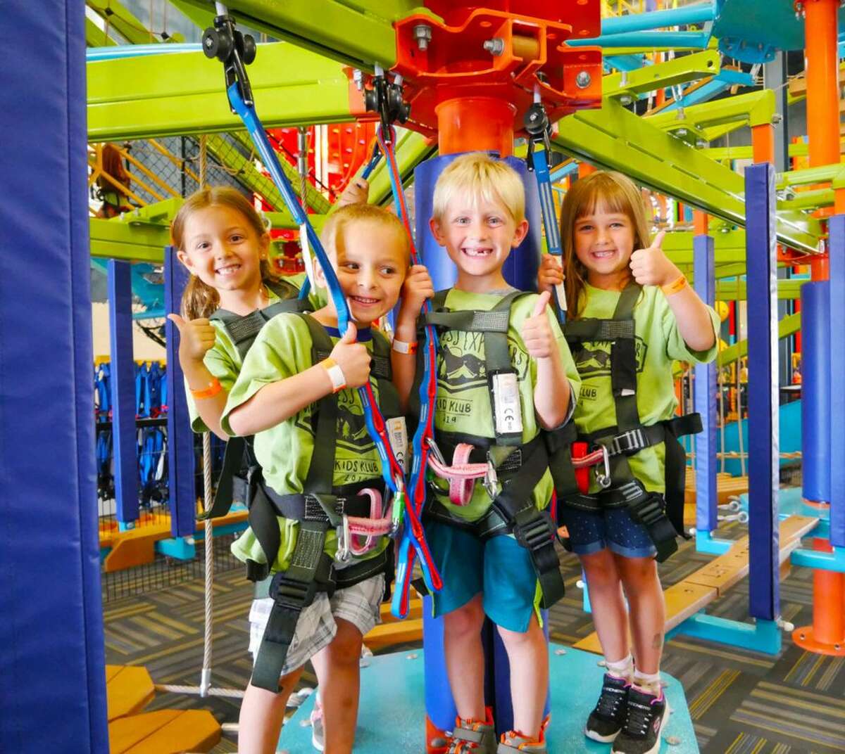 Kids wearing harnesses and standing next to the equipment at the  LiggettVille location in San Antonio, Texas.