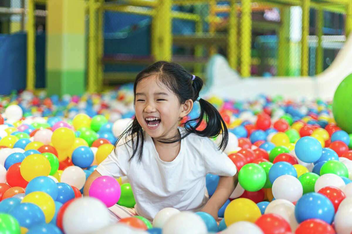 A little girl laughing in a ball pit. 