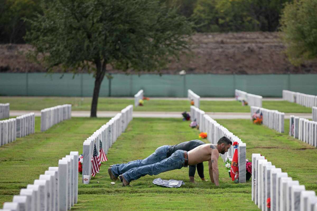 Roy Heath, fore-front, and Joshua Liserio, both of San Antonio, do pushups while visiting the grave of their best friend and fellow Marine, Alejandro A. Ramon III, at Fort Sam National Cemetery on Veterans Day.