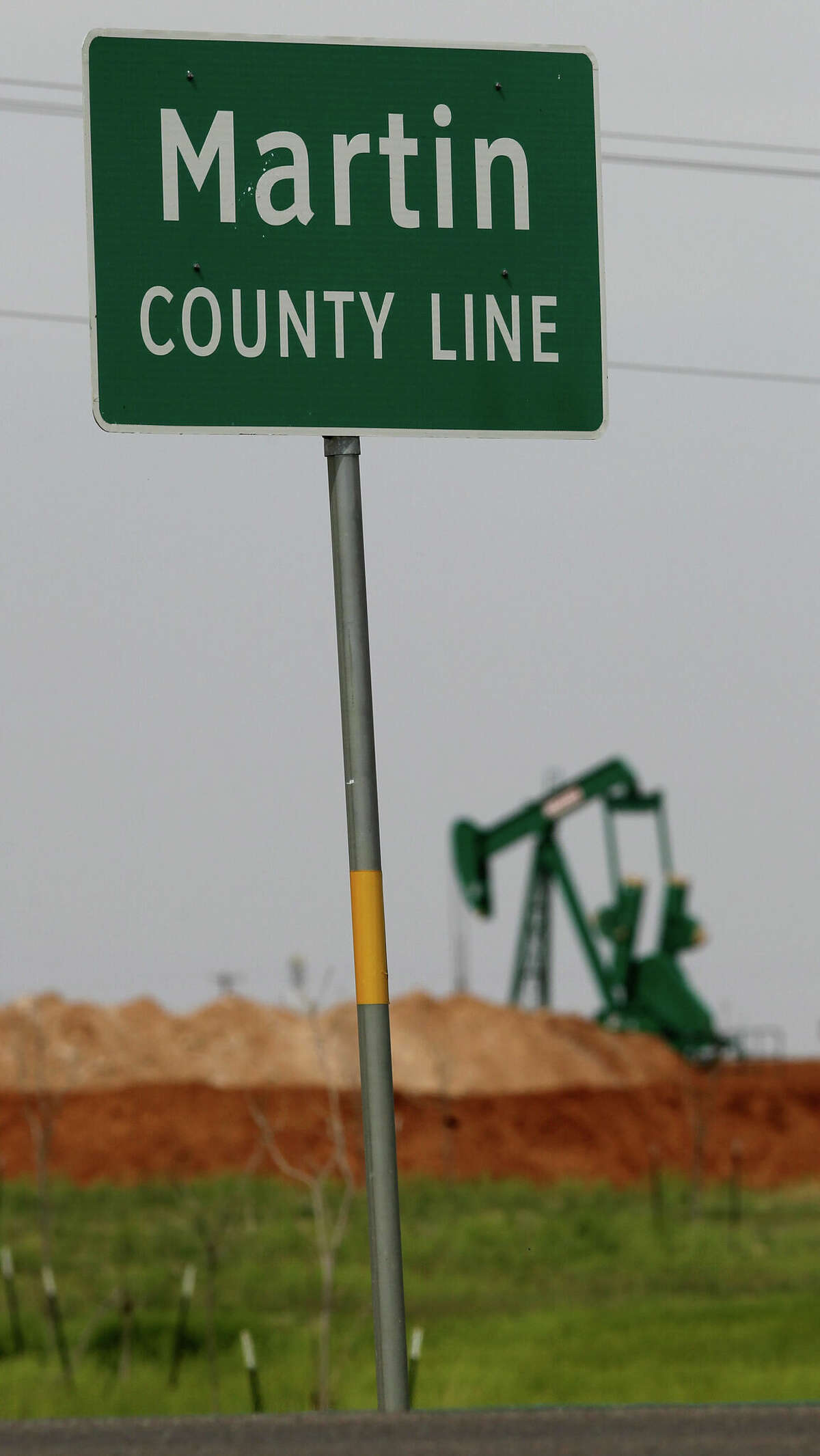 A pumpjack rocks back and forth near a sign marking the Martin County line near Stanton, April 2, 2014.