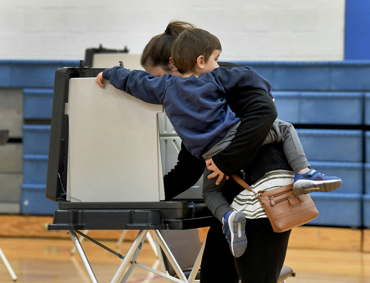 Alyssa Beck, holds her son, Henry, 3, while voting at Danbury High School Election Day Nov. 8, 2022.