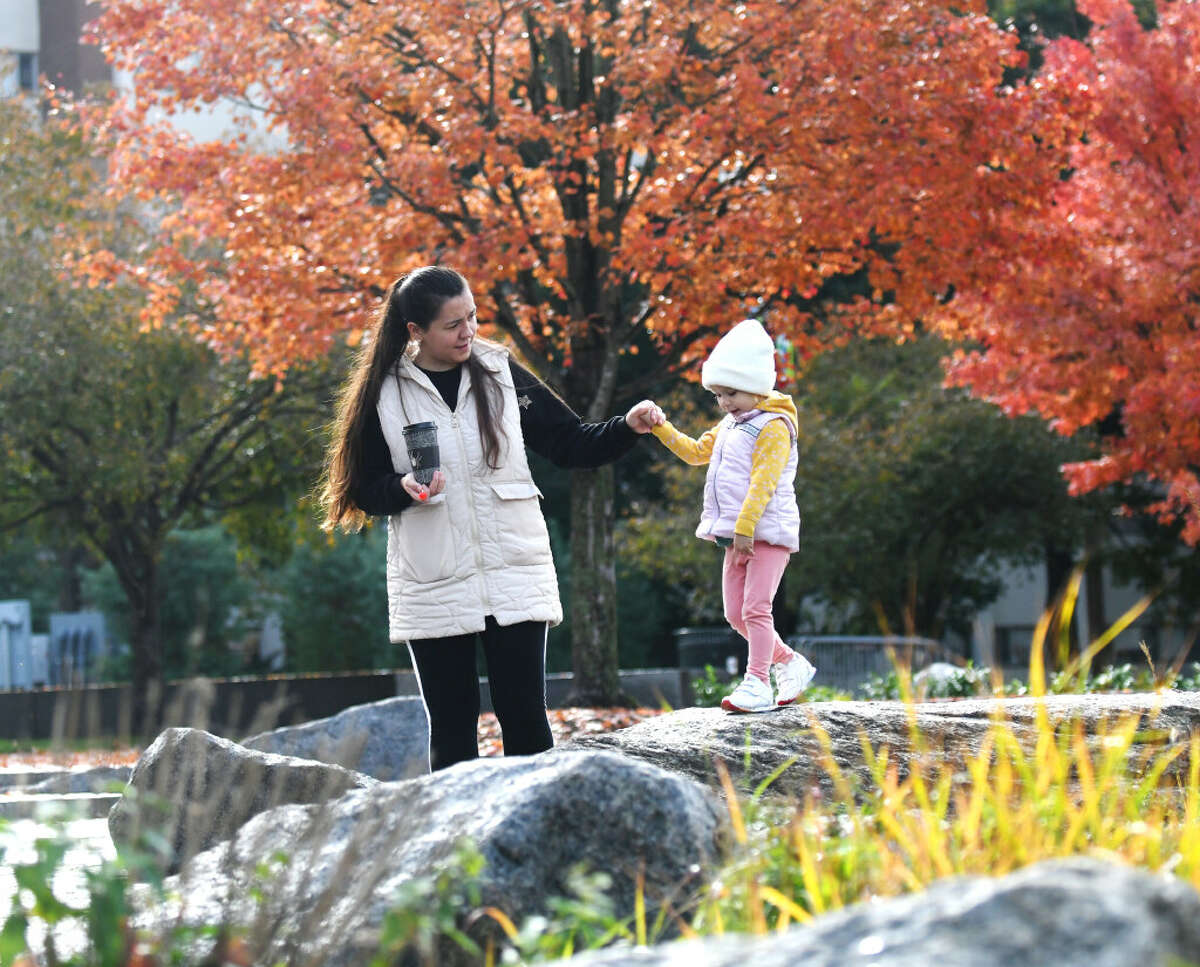 Stamford's Yuliia Franchuk and her daughter, Emilia, 2, walk through the colorful fall foliage at at Mill River Park in Stamford, Conn. Tuesday, Nov. 1, 2022.
