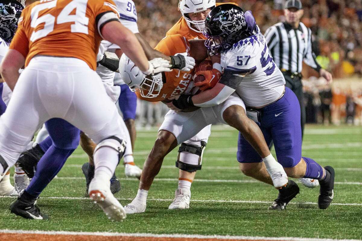 TCU linebacker Johnny Hodges (57) tackles Texas running back Bijan Robinson during the first half of an NCAA college football game Saturday, Nov. 12, 2022, in Austin, Texas. (AP Photo/Stephen Spillman)
