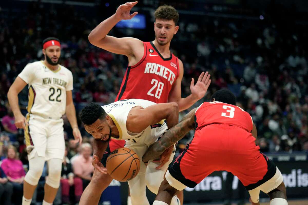 New Orleans Pelicans guard CJ McCollum struggles to control the ball as he drives between Houston Rockets center Alperen Sengun (28) and guard Kevin Porter Jr. (3) in the first half of an NBA basketball game in New Orleans, Saturday, Nov. 12, 2022. (AP Photo/Gerald Herbert)