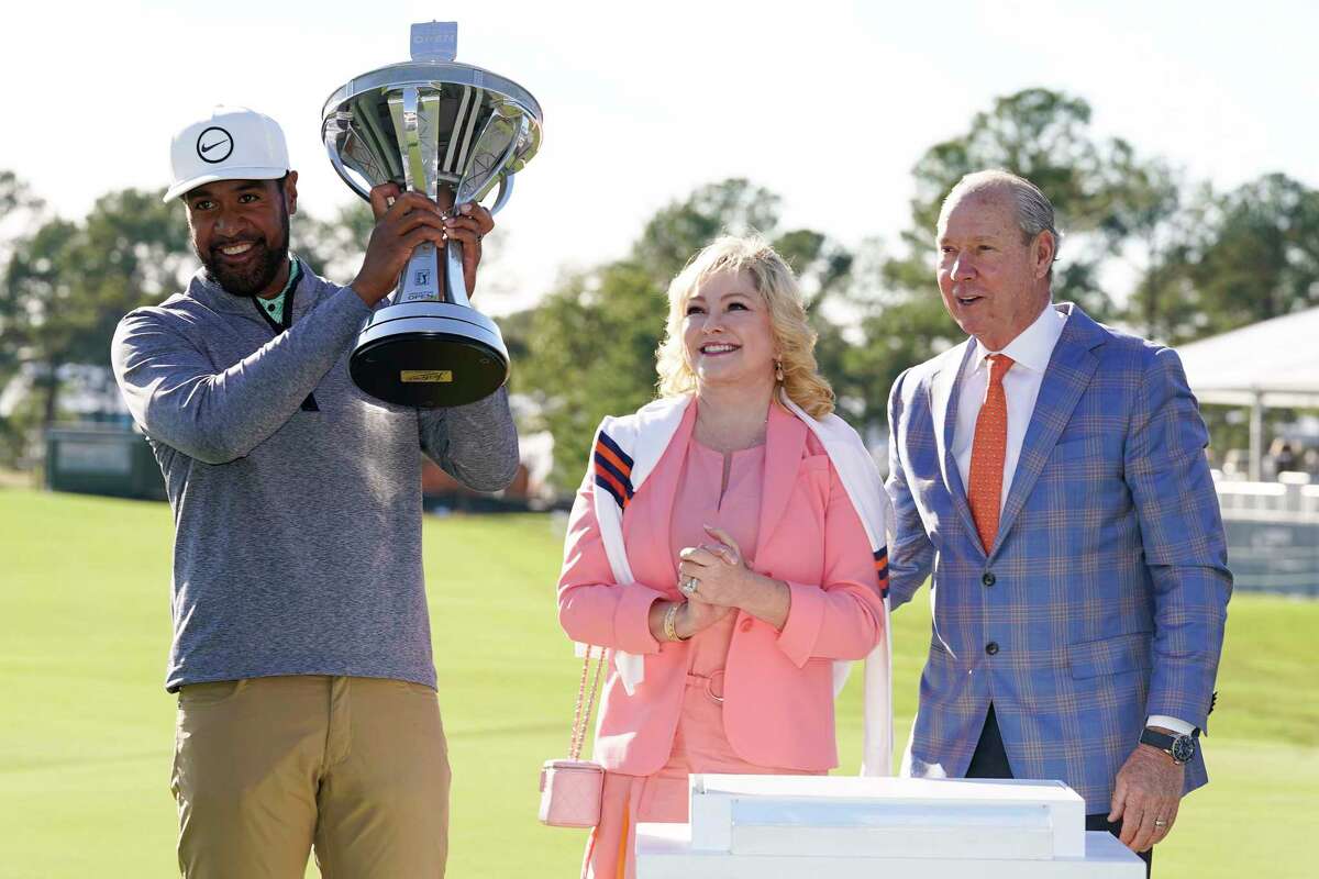 Tony Finau holds the champions’ trophy after winning the Houston Open golf tournament as Houston Astros owner Jim Crane, right, and wife, Whitney, look on, Sunday, Nov. 13, 2022, in Houston.