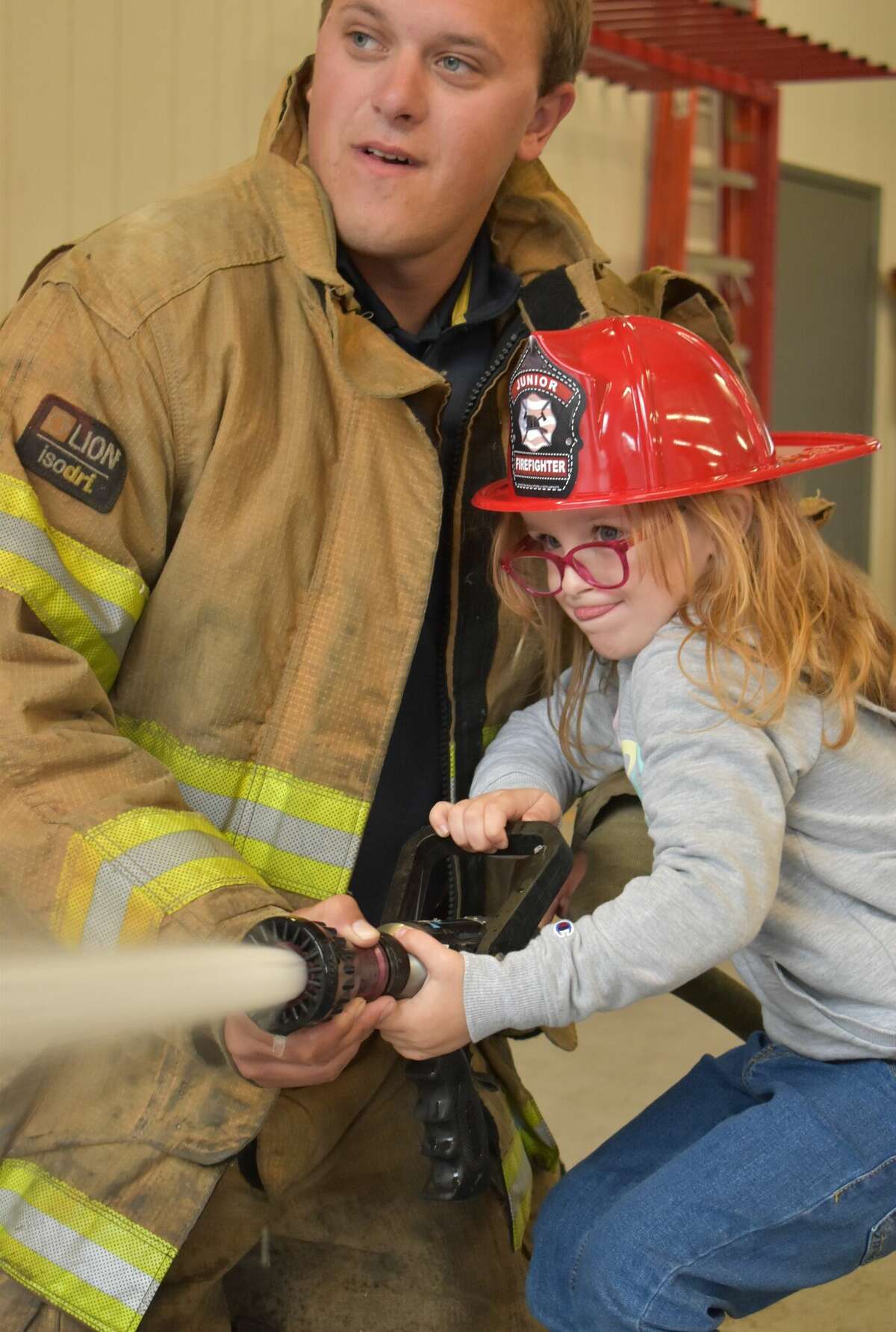 A student in Ann Edmondson's first grade class tries her hand spraying the hose during a class trip to the Bear Lake Township Fire Department.