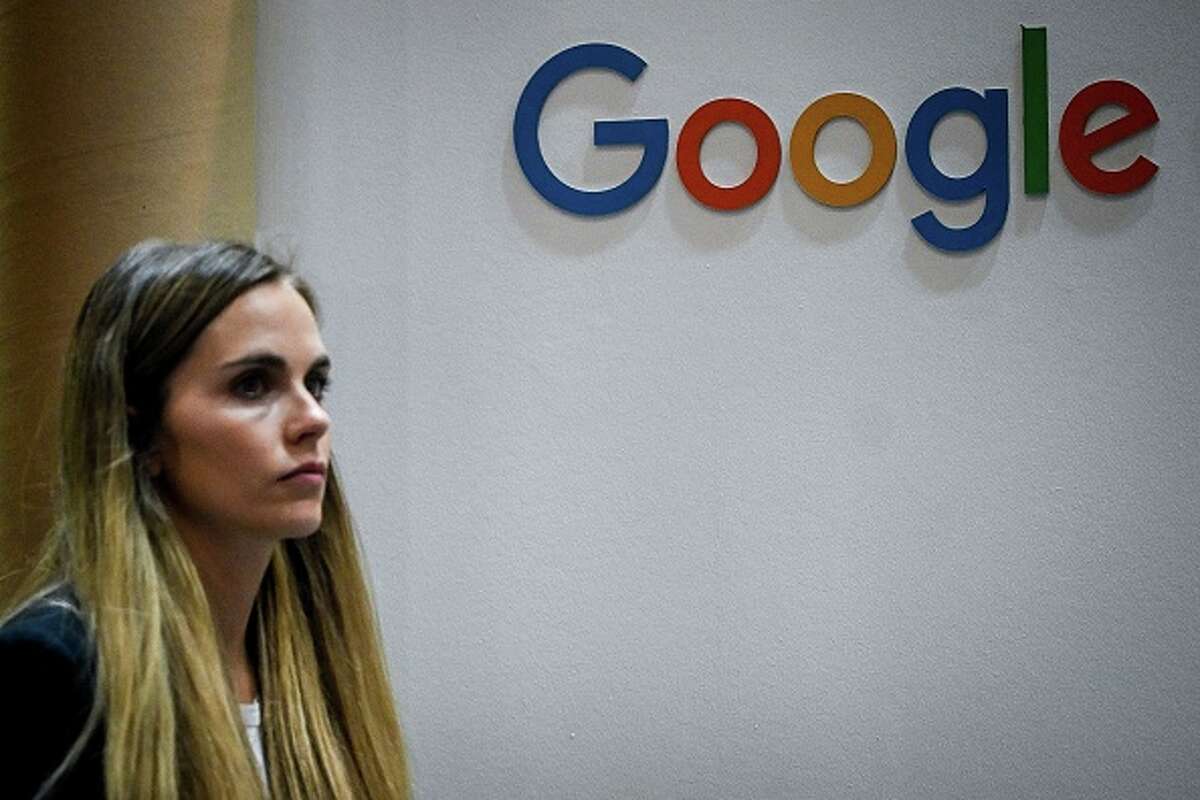 A conference attendee passes by the Google logo. The tech giant will pay Illinois $19.5 million as part of a settlement over the search engine and technology firm's location-tracking practices.