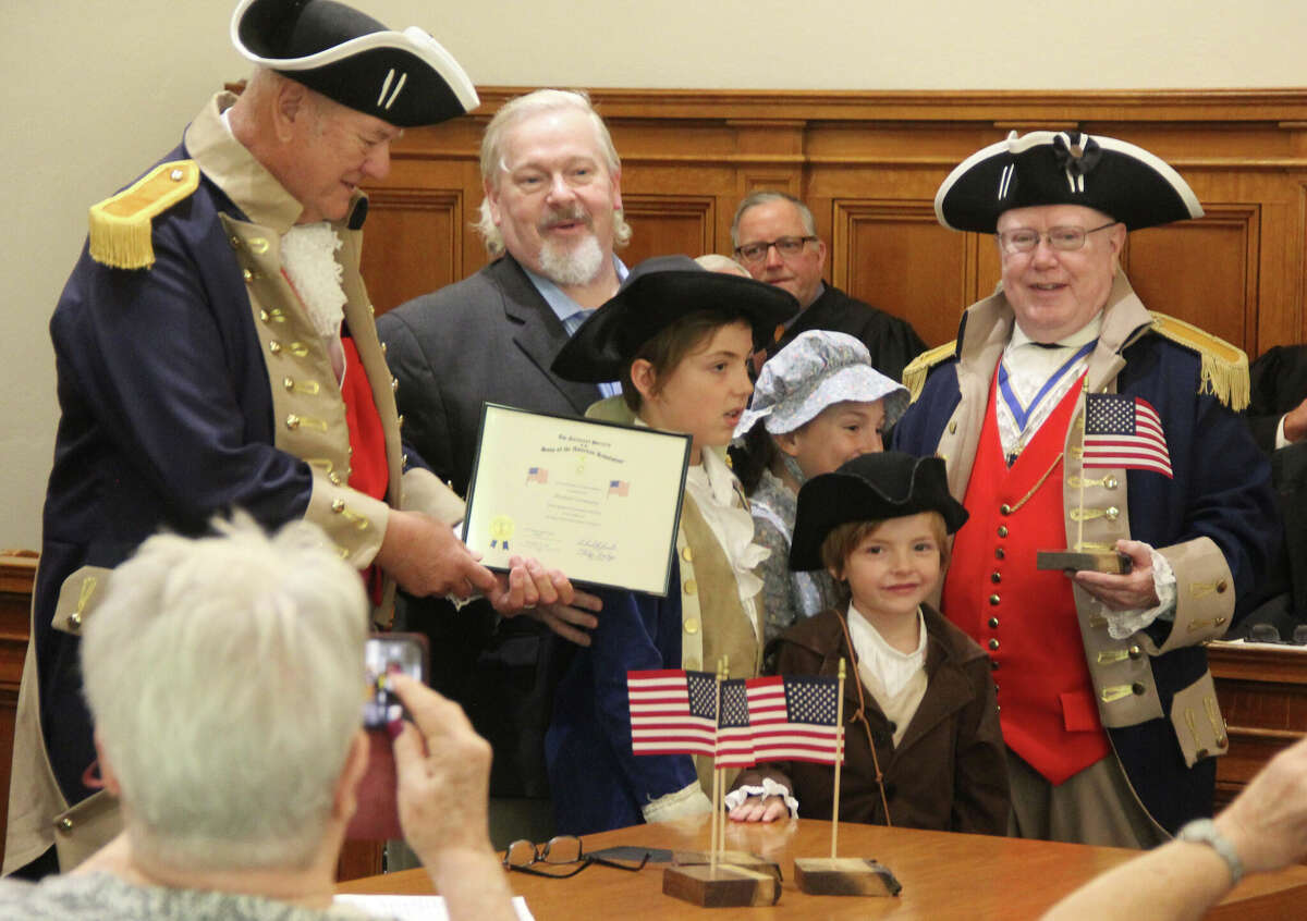 Michael Cremeens, of New Douglas, receives an award for flag display Thursday from the George Rogers Clark Chapter of the Sons of the American Revolution during a ceremony at the Madison County Courthouse. With him were his grandchildren, Jacob Sullivan, Ryan Sullivan and Everett Sullivan, who came dressed in period clothing.