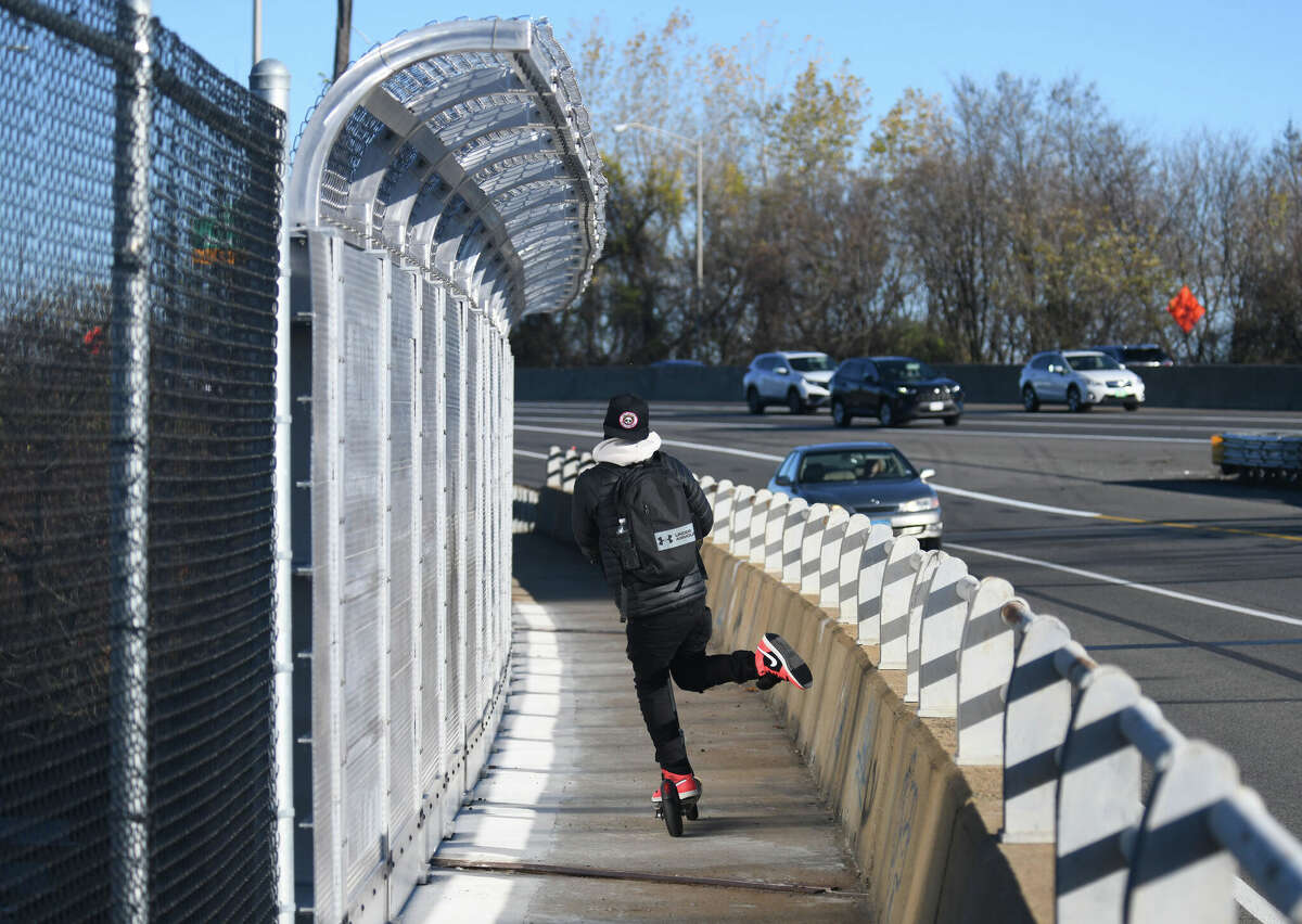 A man rides a scooter across the Yankee Doodle Bridge pedestrian walkway spanning the Norwalk River along I-95 in Norwalk, Conn. Monday, Nov. 14, 2022. After three years of shuttling pedestrians and finding alternate routes across the Norwalk River, the pedestrian walkway along the Yankee Doodle Bridge reopened last week.