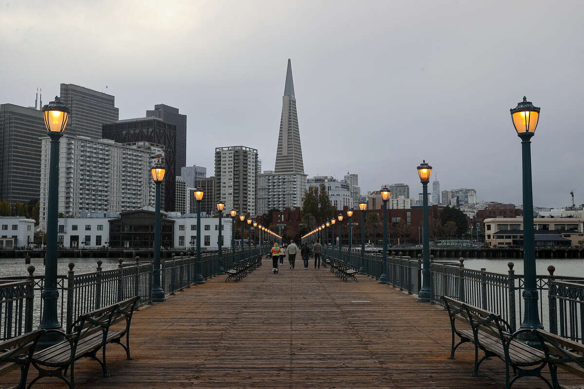 People walk on Pier 7 with the Transamerica Pyramid in the background in San Francisco on Nov. 6, 2022.