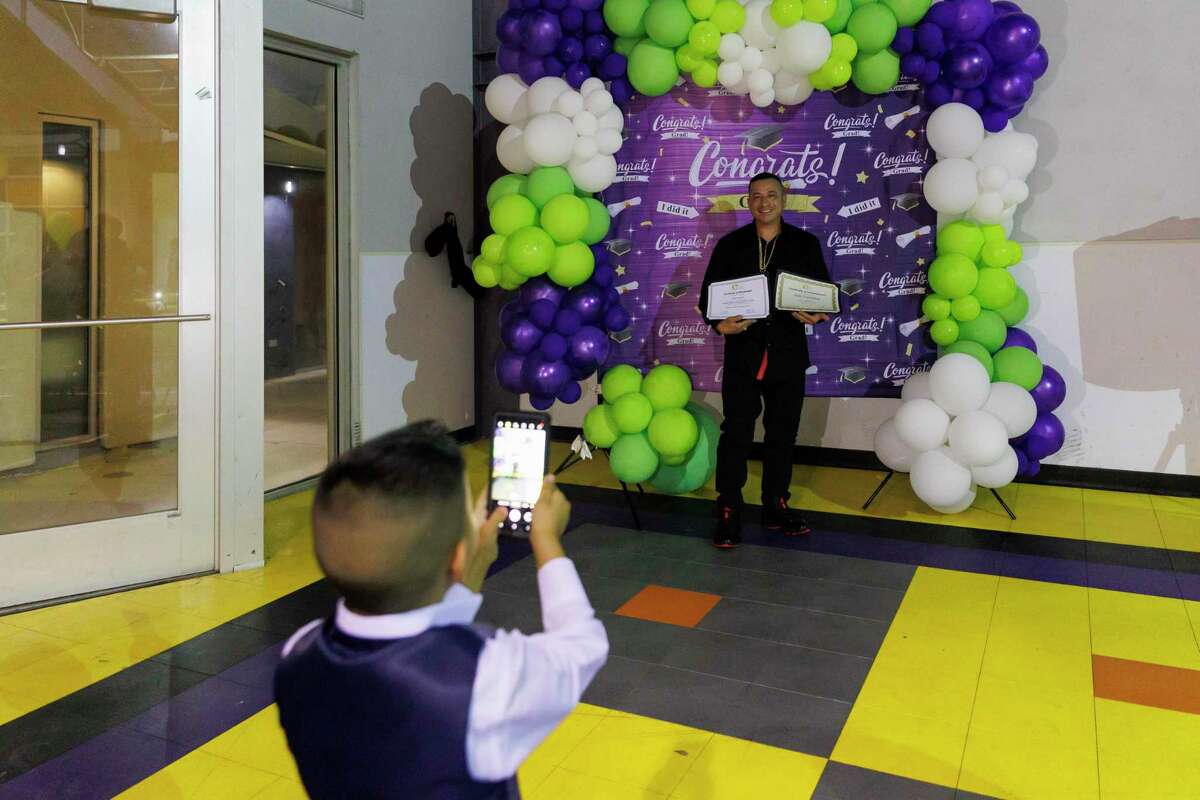 Four-year-old Julio Gonzalez takes photos of his father Julio Gonzalez during the 64th commencement ceremony for the Compadre y Compadre program at The Children’s Shelter in San Antonio on Thursday. Before receiving his graduation certificates Julio gave a speech addressing the importance of being a present father. “We talk about the ‘boy within,’ and I have a son who looks just like me,” he said.