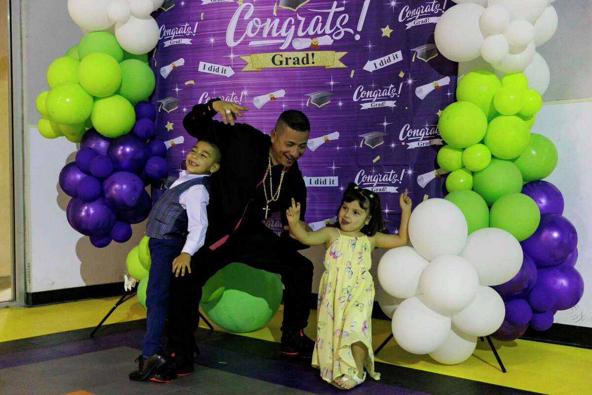 Julio Gonzalez, center, poses for pictures with his 5-year-old son, Julio, and 4-year-old daughter, Julia, during his graduation from the Compadre y Compadre program at The Children’s Shelter in San Antonio on Thursday. “You can be rich because you are breaking the cycles in your family,” Gonzalez said, as he talked about building generational wealth for his children in other ways besides money.