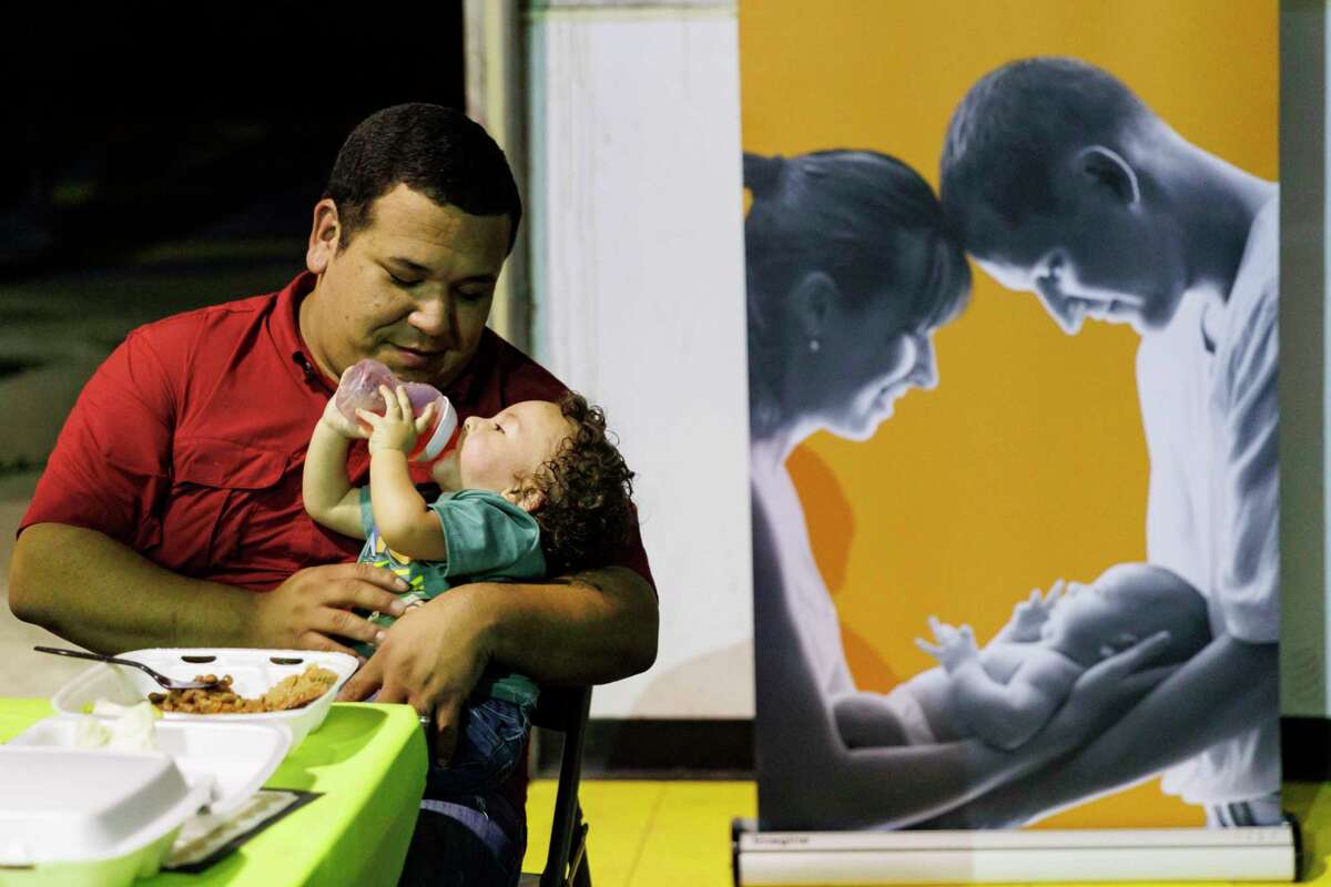 Michael Regino embraces his 1-year-old son Zachary while eating dinner during the graduation ceremony for fathers enrolled in the Compadre y Compadre program at The Children’s Shelter in San Antonio on Thursday. Regino graduated from the 15-week course that emphasizes strengthening the male caregiver’s role with their children and family.