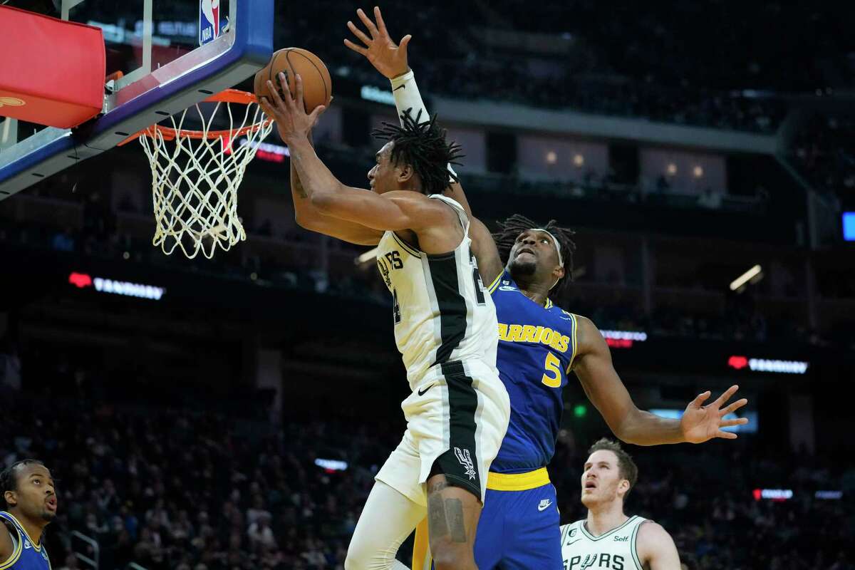 San Antonio Spurs guard Devin Vassell, center left, shoots while defended by Golden State Warriors center Kevon Looney (5) during the first half of an NBA basketball game in San Francisco, Monday, Nov. 14, 2022.