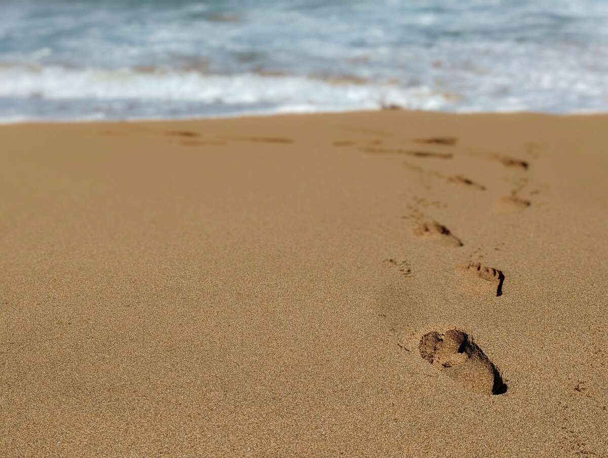 Footprints leading to the waves at Kauai’s "secret" Kauapea Beach.