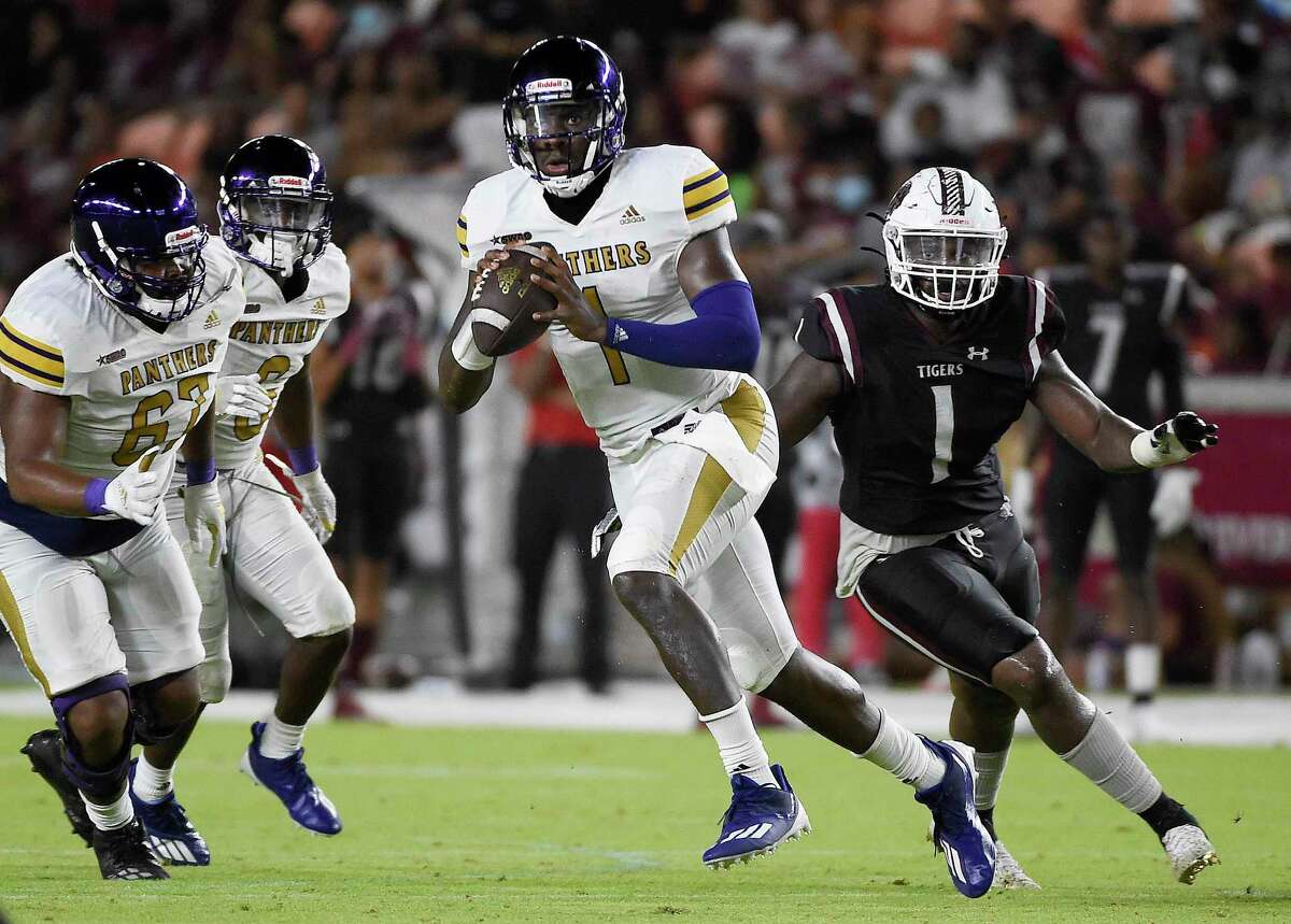 Prairie View A&M quarterback Jawon Pass, center, scrambles away from Texas Southern defensive end Michael Badejo (1) during the second half of an NCAA college football game, Saturday. Sept. 4, 2021, in Houston.