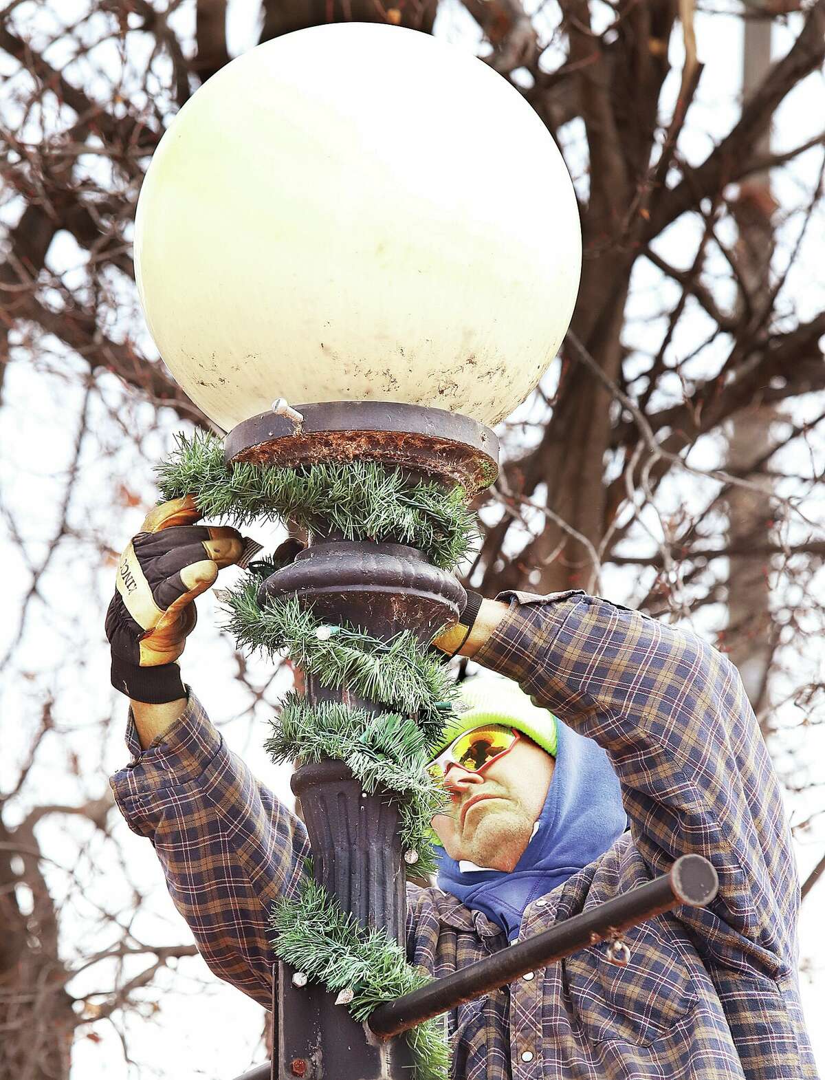 John Badman|The Telegraph An Alton Park and Recreation Department employee works to wrap the decorative light pole in Lincoln-Douglas Square with lighted garland Wednesday as the square is prepared for the 28th Annual Community Tree Lighting on Friday. Santa Claus will arrive again this year by trolley at 6 p.m. and the free event includes cookies, hot cocoa and caroling. Alton Mayor David Goins will light the brand new Christmas tree, provided by the Alton-Godfrey Rotary Club, at 6:45 p.m. Trolley rides will be offered 5:30-7:30 p.m. and carriage rides will be available 7-9 p.m.