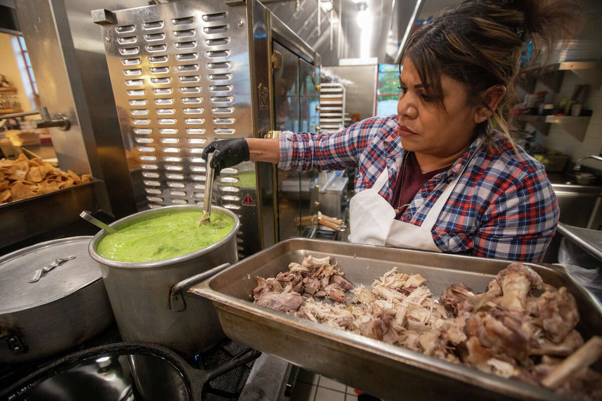 Kitchen staff member Melida Rodriguez adds shredded chicken to the green pozole served at Bombera in Oakland. 