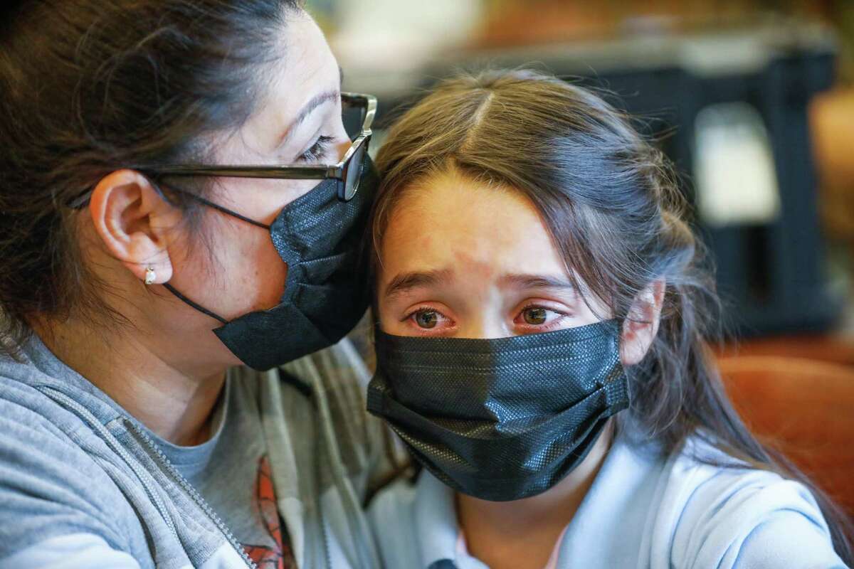 Xochitl Escobar (left) embraces granddaughter Shelssie Rodriguez Molina, 7, before she got the COVID-19 vaccine and flu vaccine in 2021 in Richmond. Health officials are concerned about a rise in cases of flu and other respiratory diseases causing a spike in visits to emergency rooms, and they advise parents to take precautions such as wearing masks and getting their children the appropriate vaccinations.