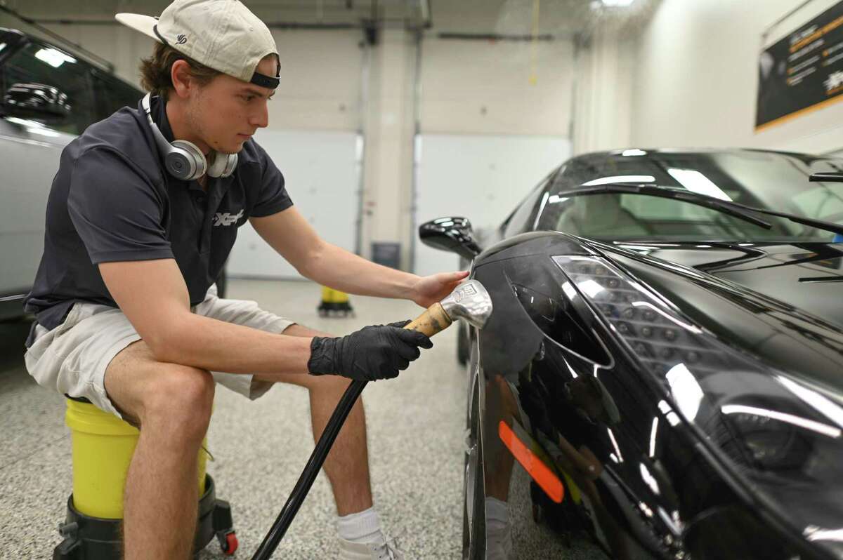 Cody Phillips works on applying the protective film made by XPEL Inc. to a vehicle at the company’s headquarters.