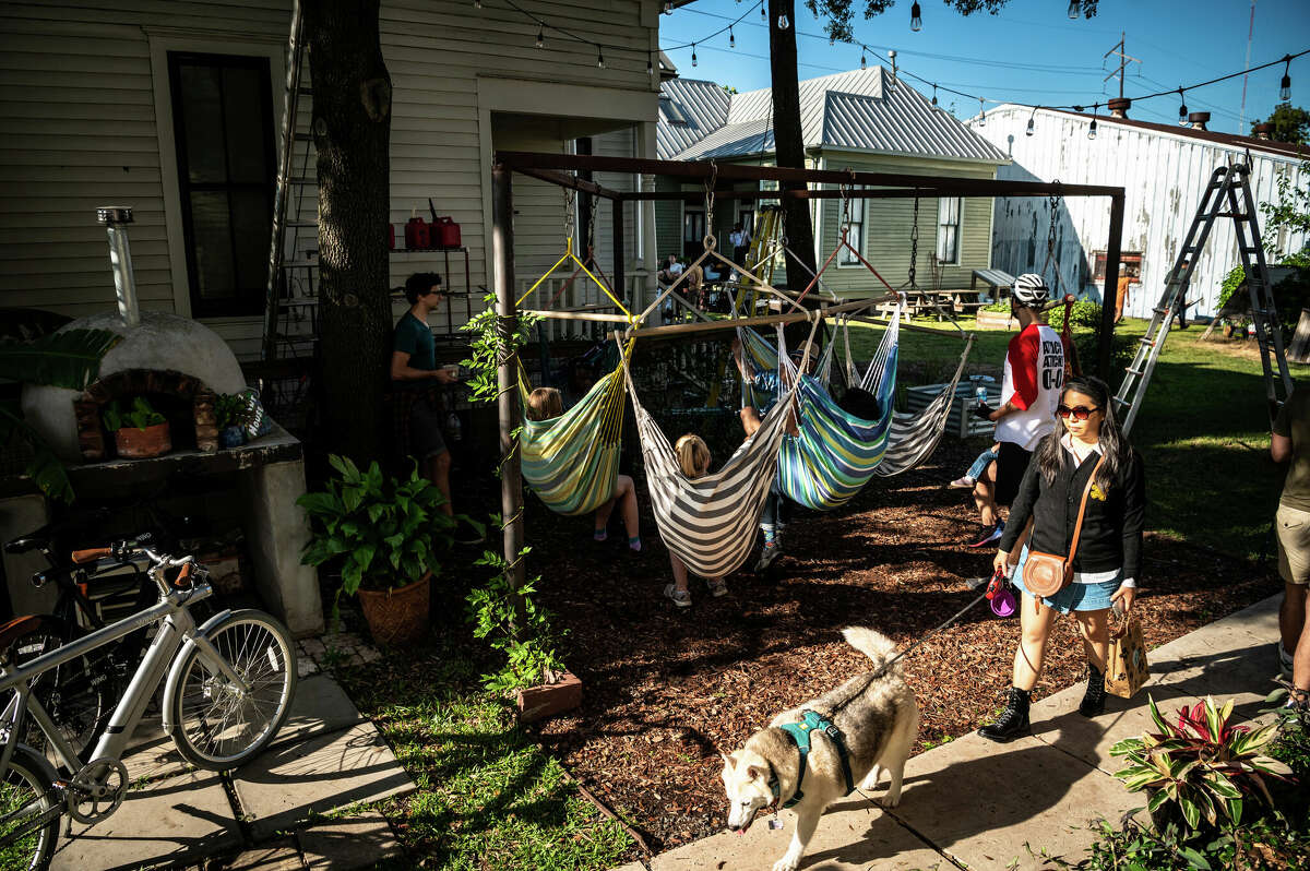 Members of a local bicycle club relax in hammocks at The Plant House, a renovated 1890s house and AirBnB rental in the heart of Concept Neighborhood's development project in the Second Ward, on Saturday, November 5, 2022 in Houston, Texas. The developers aim to design several blocks in a socially conscious way that is pedestrian and bike-friendly and uplifts local residents and small businesses. 